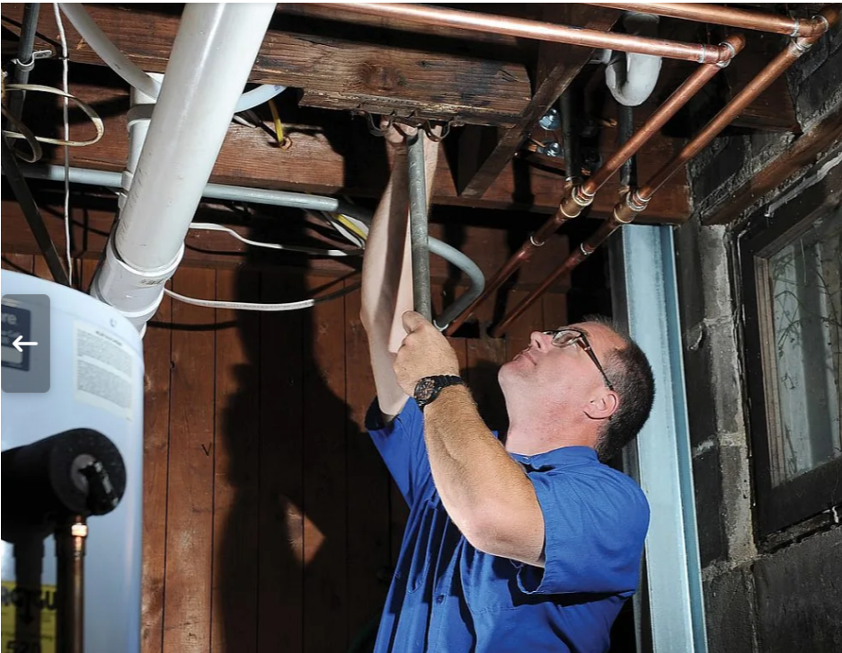 Plumber working near water heater in a house.