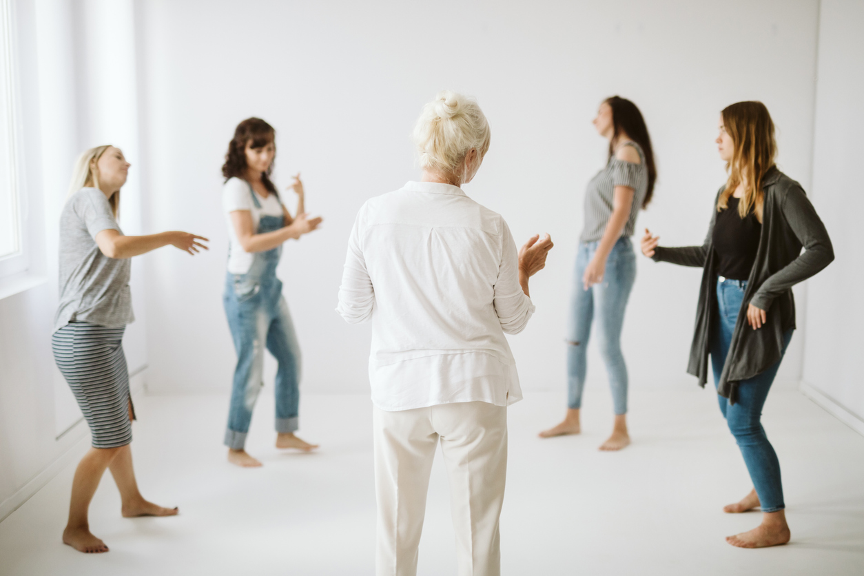 Five women expressing themselves in a circle participating in dance therapy. 

