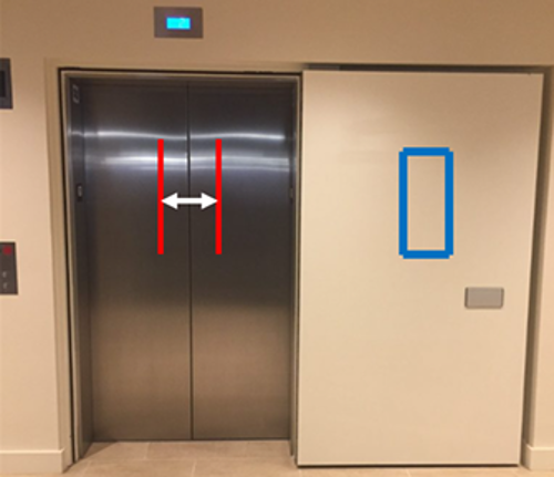Elevator with a solid smoke door to the right of the elevator doors and no vision panel in the center. There is a rectangle in the center of the smoke door to show where the vision panel would need to be and an arrow and two parallel lines in the center of the elevator door showing where the vision panel would land when the smoke doors are activated.