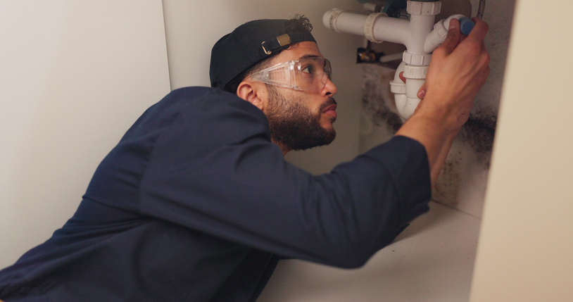 Plumbing contractor working on filter system improvement for small business in house.