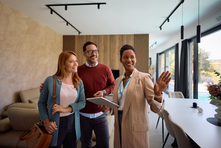 Real estate agent using digital tablet while showing new house to a couple.

