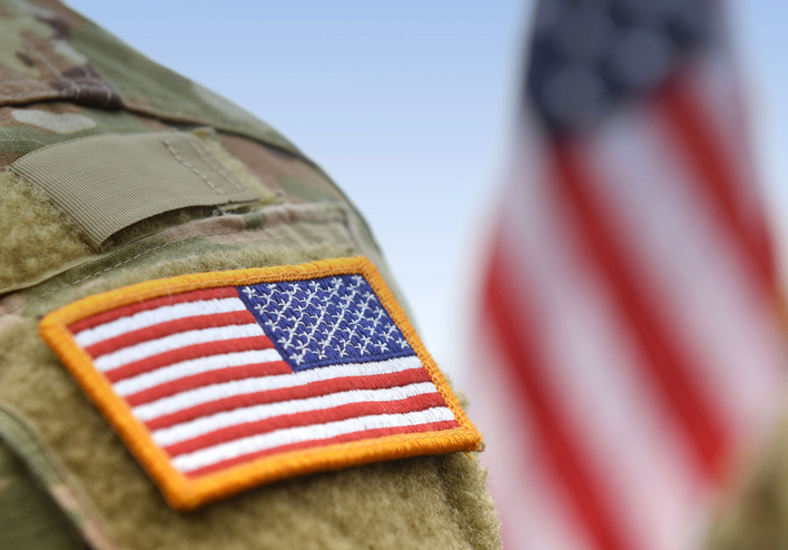 Image of a military veteran's shoulder with the American Flag in the background. 