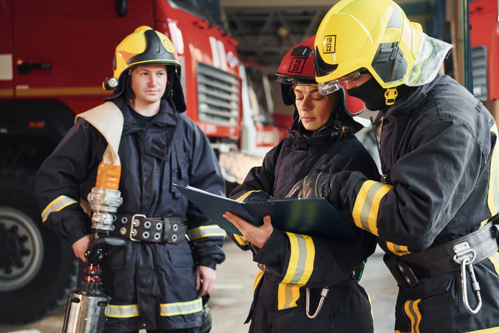 Group of firefighters in protective uniform reviewing safety standards.