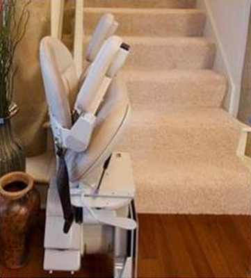 Stairway chairlift in the Folded position at the base of a set of stairs.