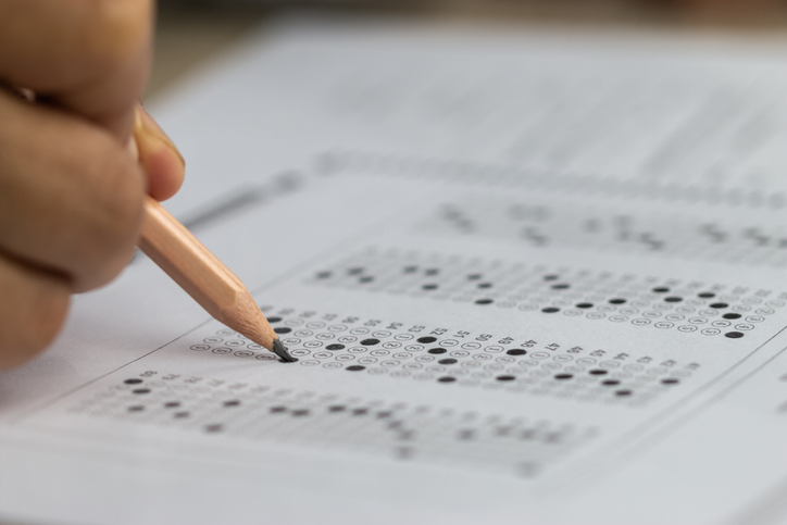 An image of a hand of a test taker with their pencil taking an exam.