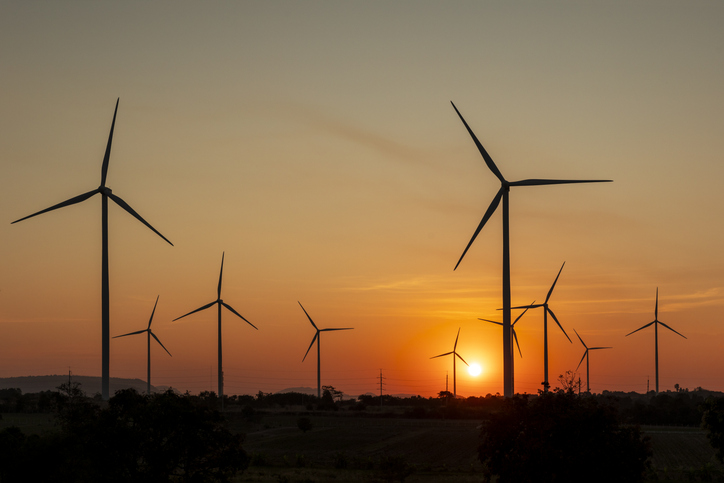 Silhouette of wind turbines farm with beautiful orange sunset background.

