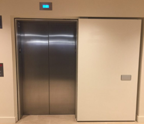 A smoke door on an elevator that is slid to the side to allow entry or exit to the elevator door.