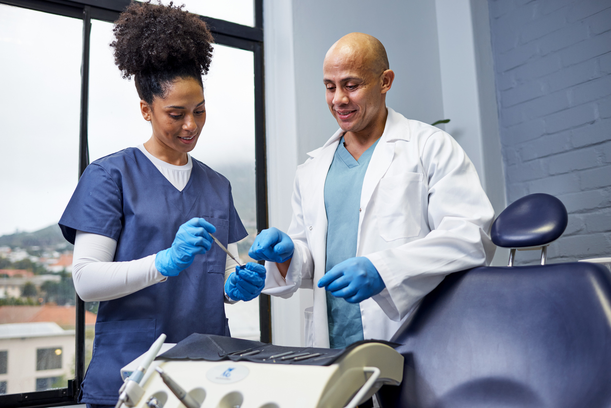 Two cheerful dental practitioners collaborating in a modern dental office, discussing professional tools while sharing a positive interaction.