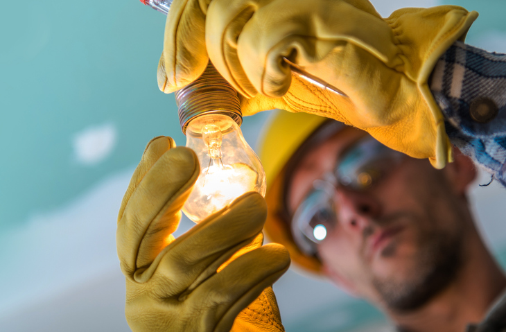 Closeup photo of worker installing a professional electric light. 