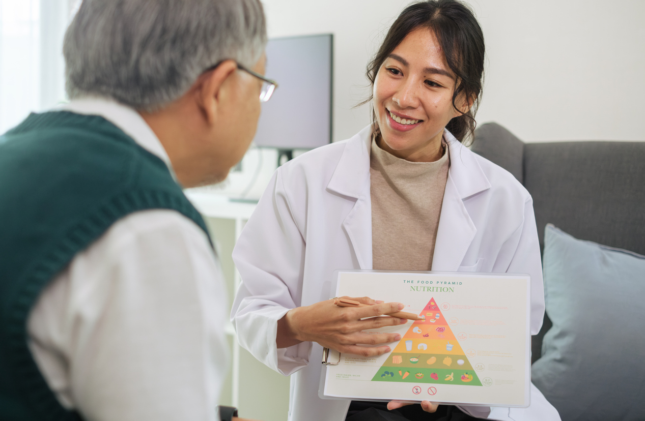 Dietician Explaining Healthy Eating and Food Pyramid to Senior Patient During Nutrition Counseling

