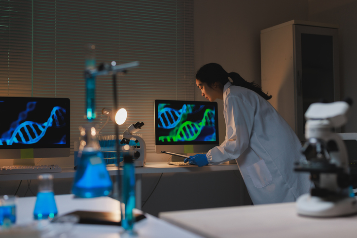 Young scientist analyzing DNA structures on computer screen in research laboratory.

