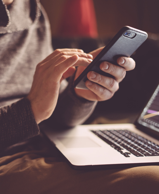 Man using smartphone and laptop.

