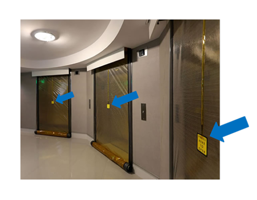 Three elevators with smoke curtains deployed with blue arrows pointing at the center of the curtains to show the area where the curtain can be retracted or break away so a firefighter can enter or exit a landing. 