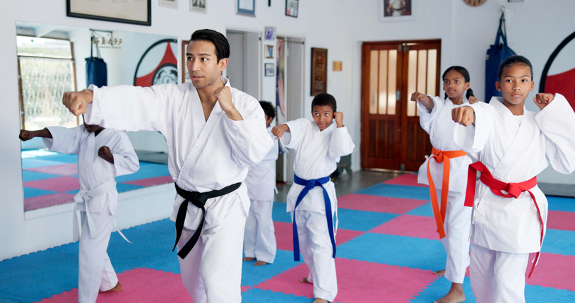 Male instructor with children in karate class teaching them self defense training. 