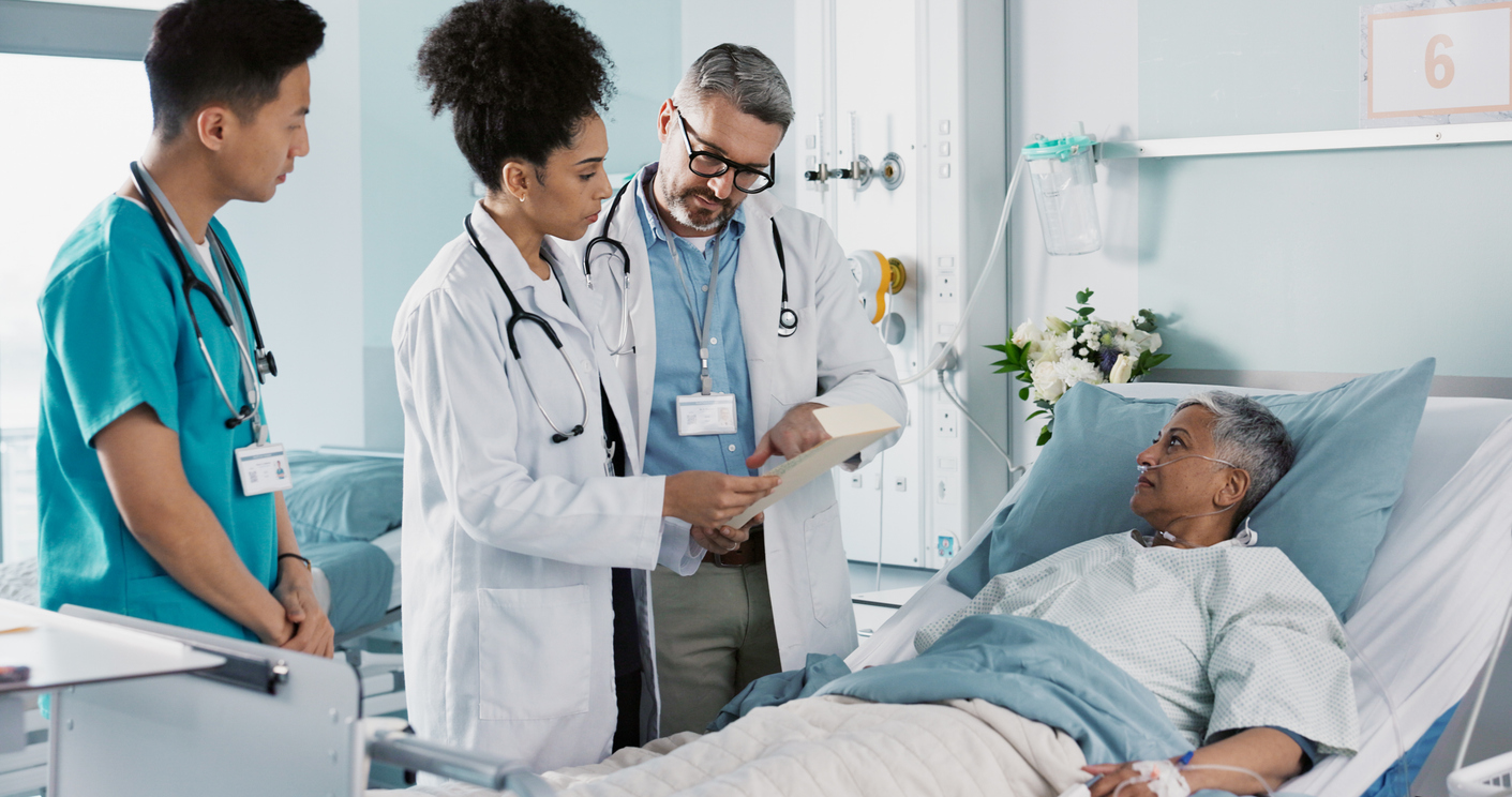 Male and female doctor check on a patient in a recovery room of a hospital. 
