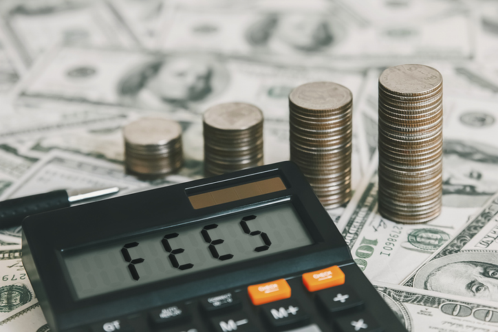 An image of a calculator on a table full of money spelling out the word fees. 