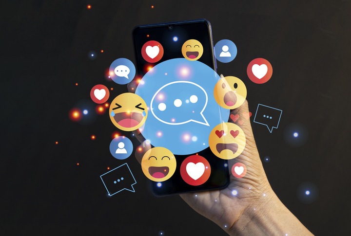 Use of social media featuring various emojis on a phone. 