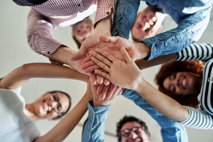 Low angle portrait of a group of smiling coworkers in a huddle.

