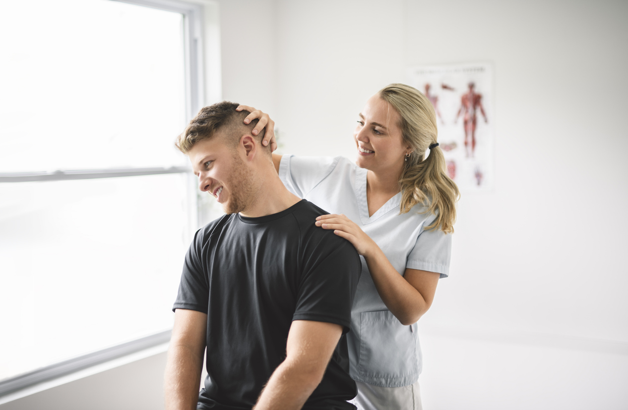 A female chiropractic technician working with a male client on neck treatment. 

