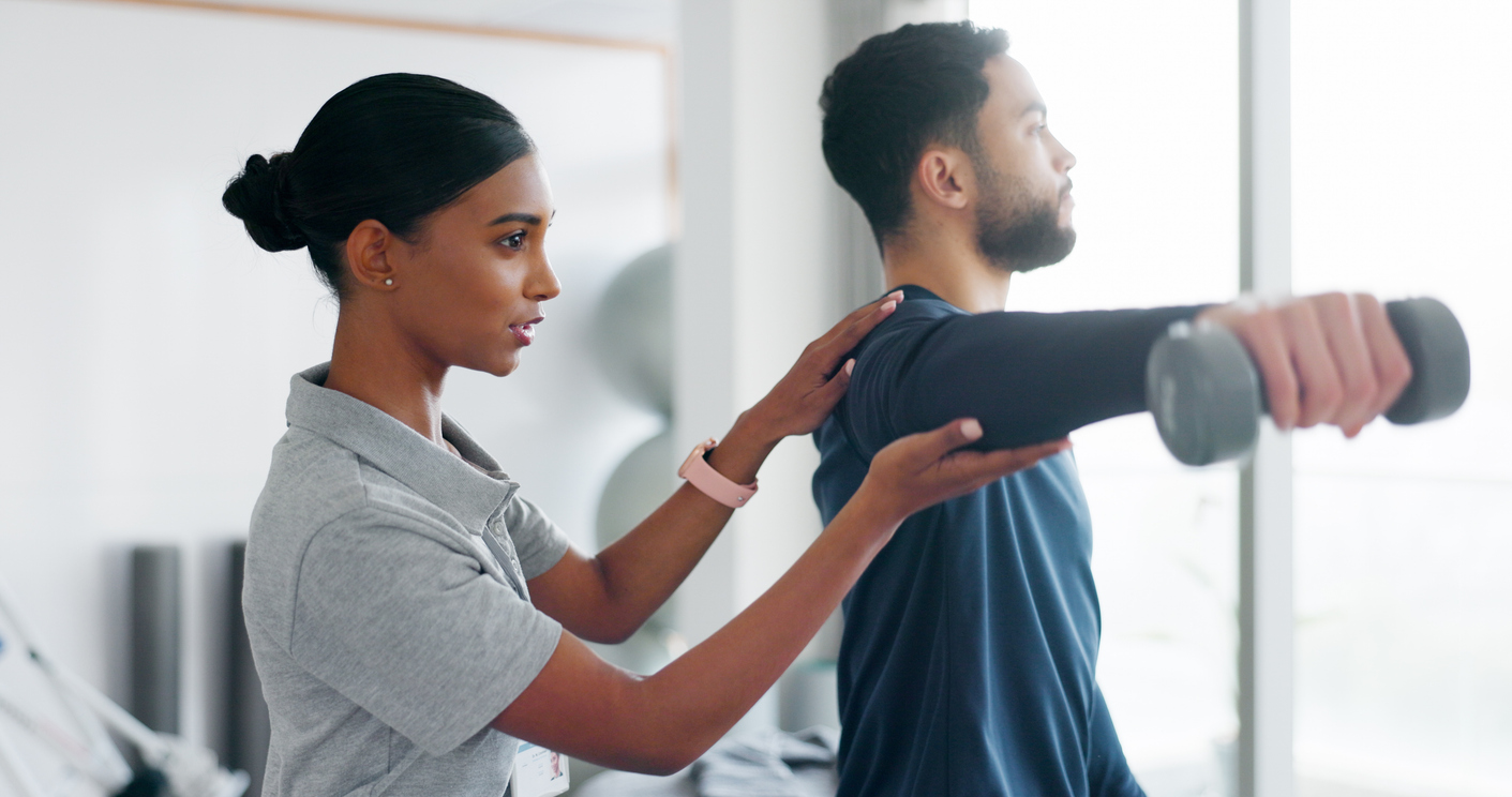 Female therapist assisting male patient with dumbbell exercises for rehabilitation and mobility. 