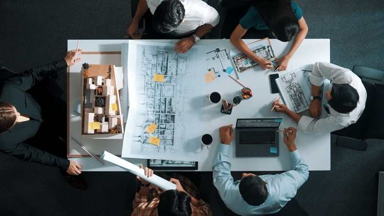 Aerial view of architects working together on a document at meeting table.