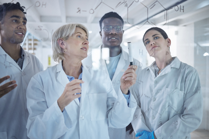 Diverse team of scientists sharing ideas and brainstorming while standing in a meeting together. 